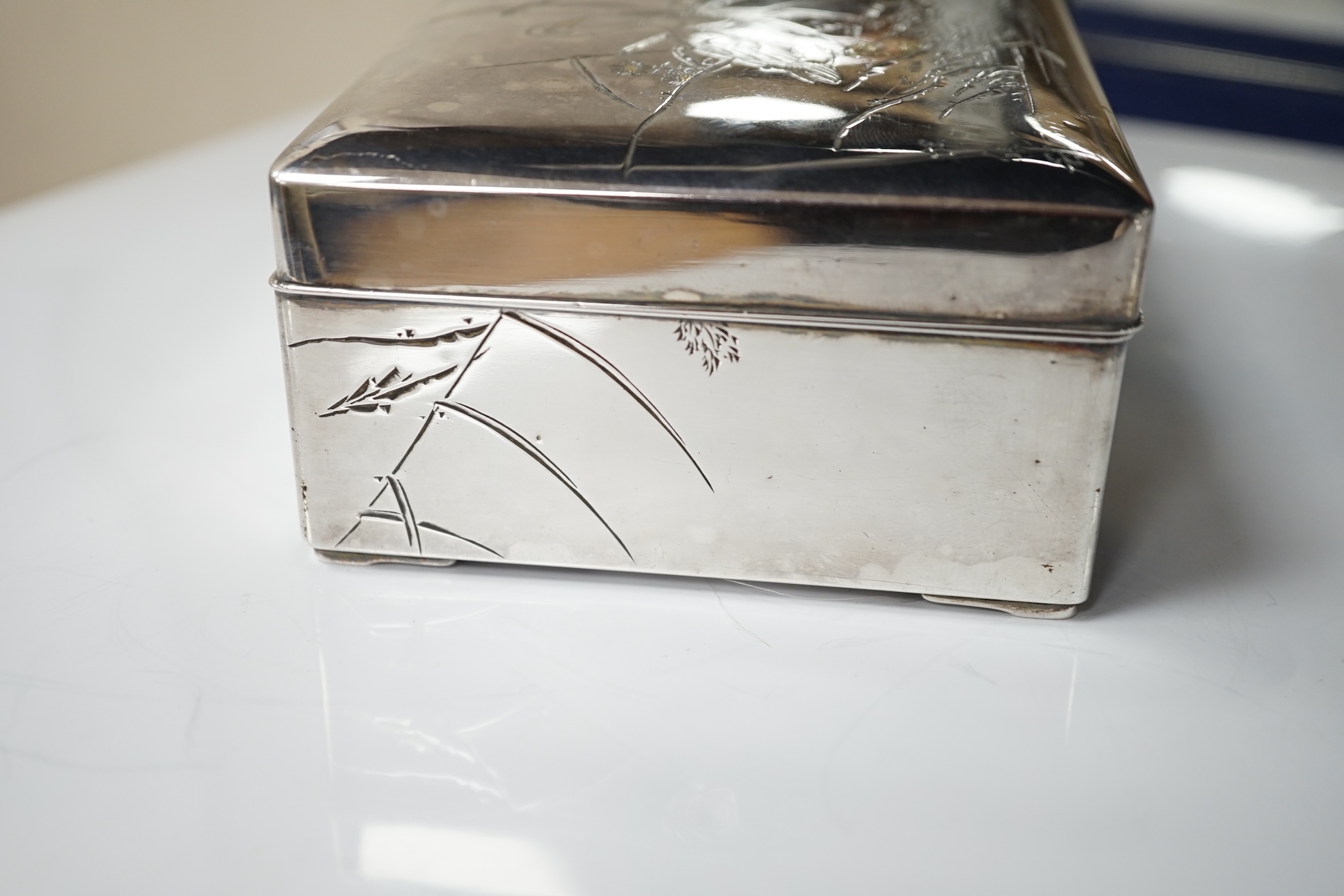 A Japanese white and yellow metal mounted rectangular cigarette box, engraved with birds and reeds, signed to the base, 14.2cm. Condition - fair